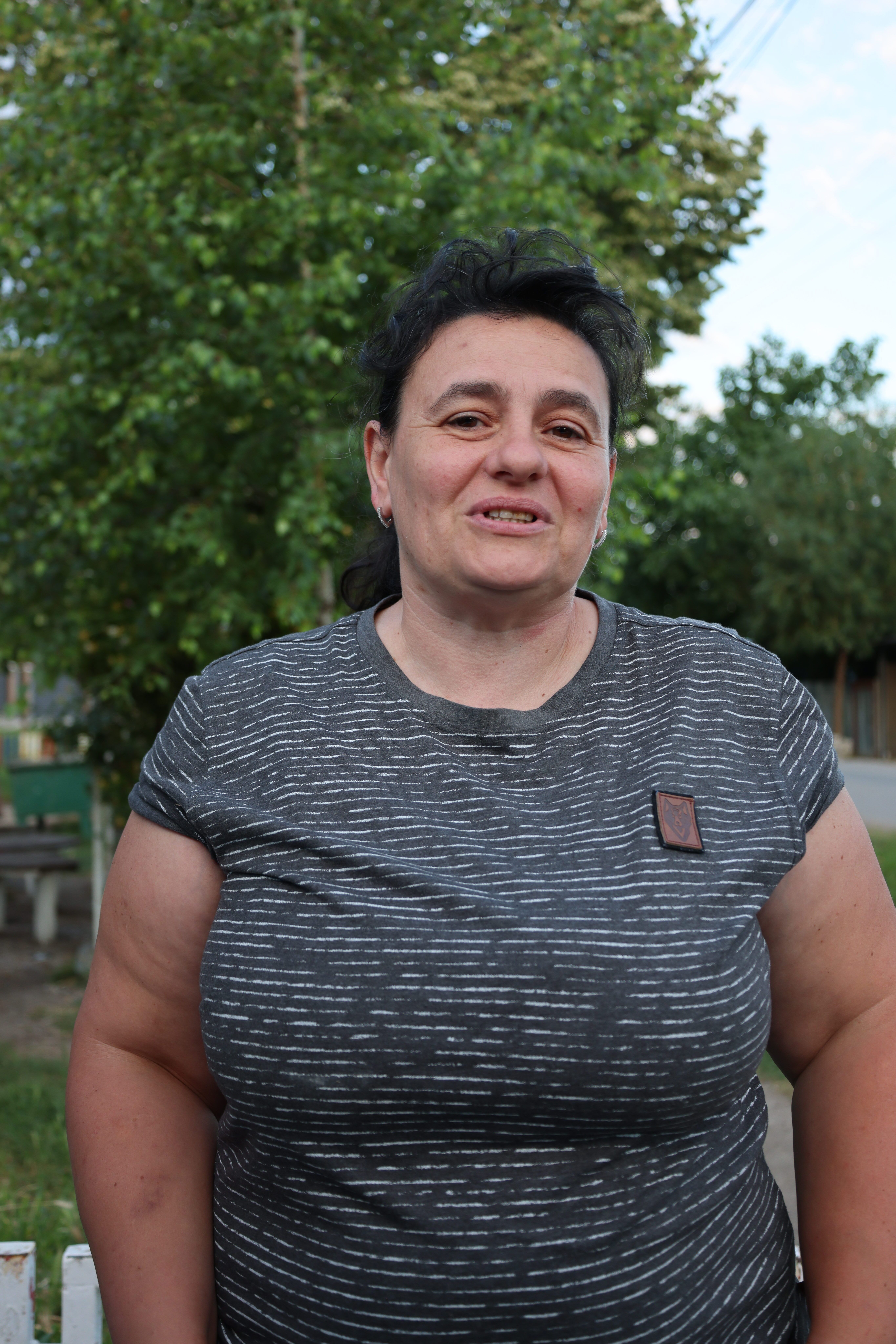 Woman smiling outdoors in a casual setting, showcasing natural beauty.
