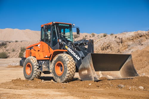 A orange wheel loader on a dirt road