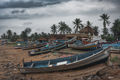 Charming view of a tropical coastal village with colorful fishing boats and lush palm trees.