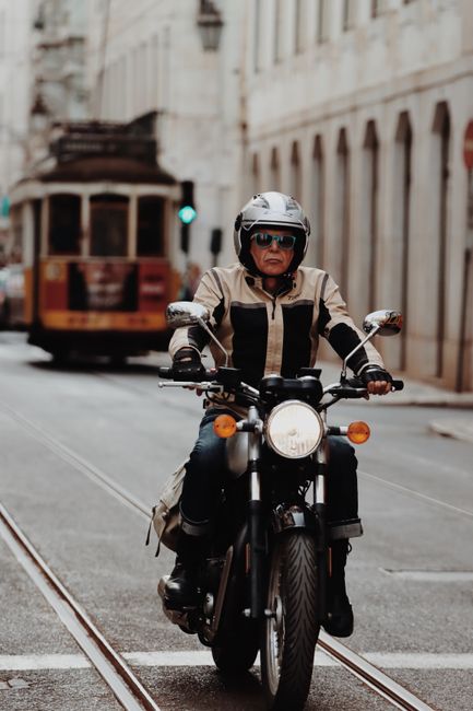 A motorcyclist rides through Lisbon's charming streets with a vintage tram in the background.