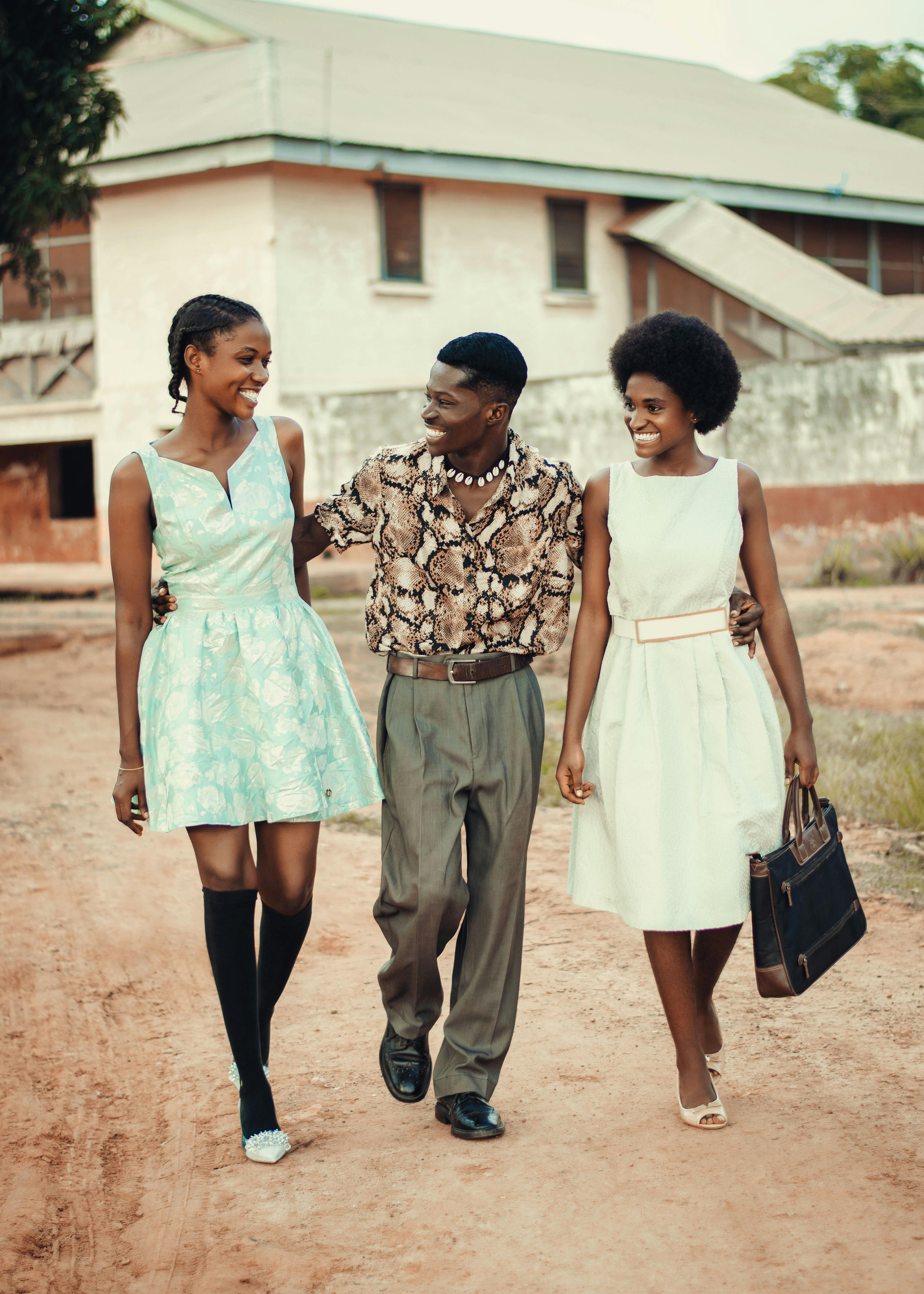 Three friends walking and smiling in a village atmosphere featuring fashion styles.