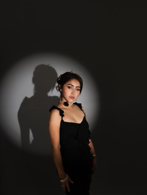 A woman in a black dress is standing in front of a light