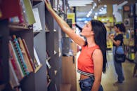 在当代书店，一名穿着休闲装的年轻女子从书架上拿起一本书