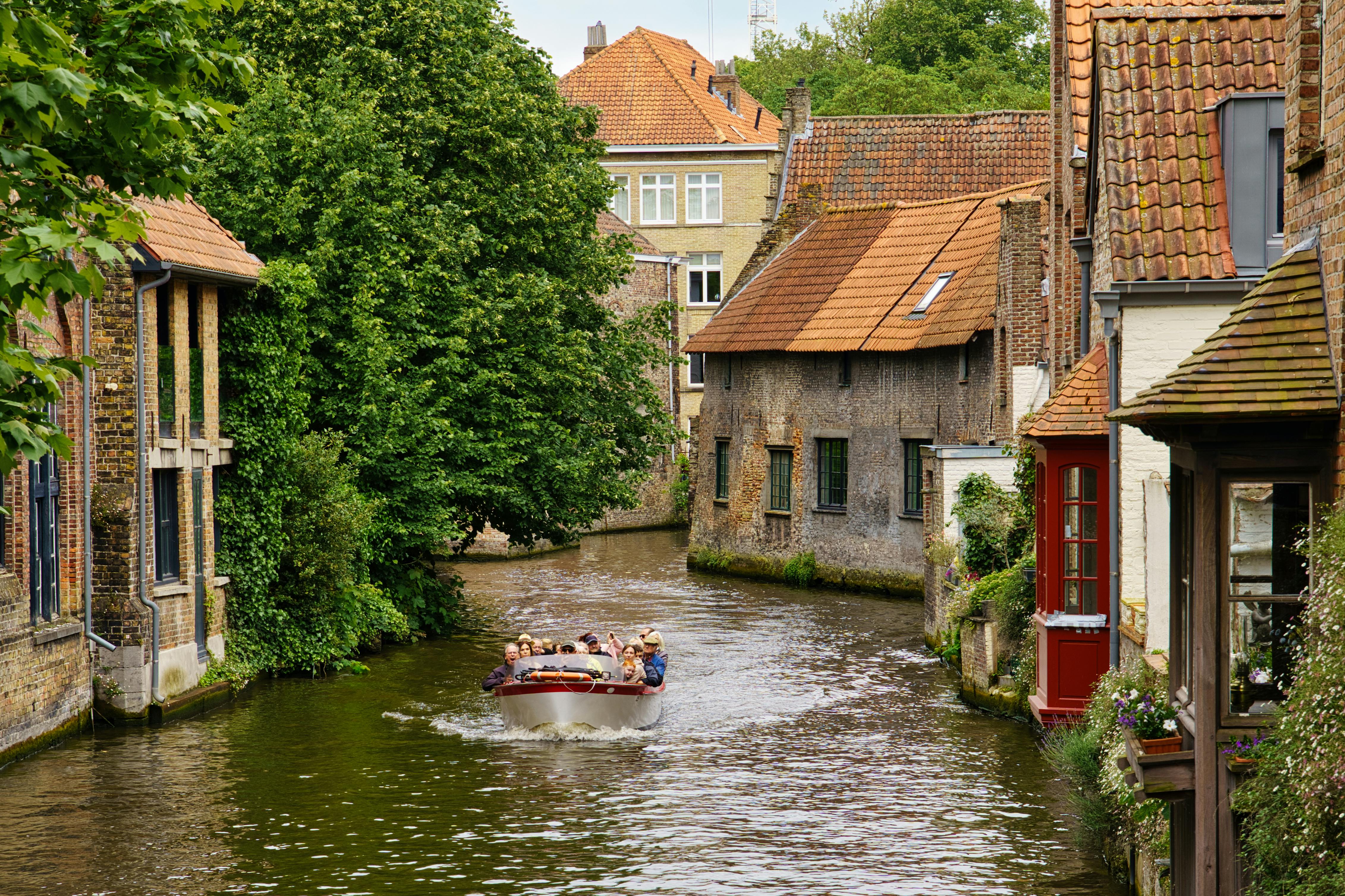 Explore a picturesque canal with historic houses and a scenic boat tour in Bruges, Belgium.