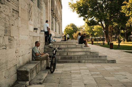 Free People sitting on stone steps by a building in an urban park during summer. Stock Photo