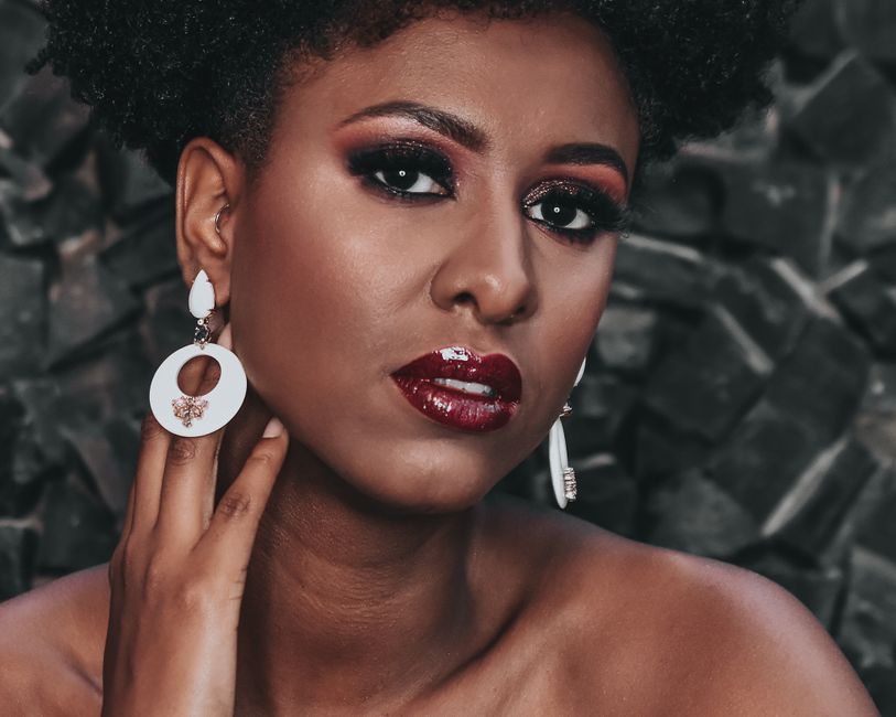 Captivating close-up portrait of a beautiful woman with striking makeup, red lipstick, and stylish earrings.