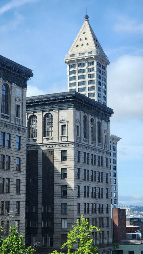 Free Historic Smith Tower in Seattle framed by modern urban landscape under clear blue skies. Stock Photo