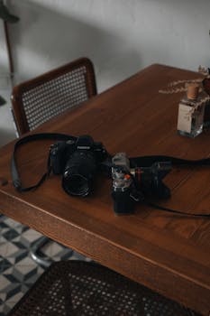 A collection of cameras and lenses on a wood table, perfect for photography lovers.