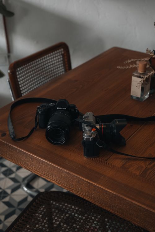 Free A collection of cameras and lenses on a wood table, perfect for photography lovers. Stock Photo