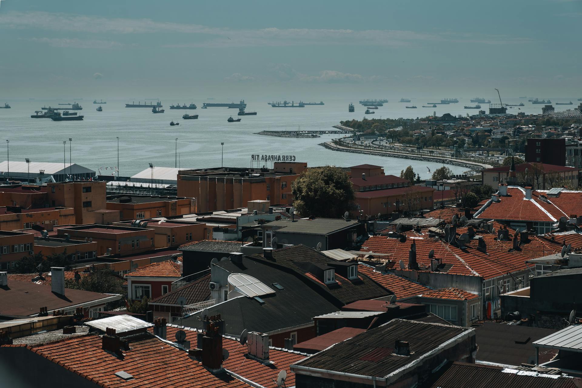 Aerial view of Istanbul's rooftops with the Bosphorus Strait and shipping vessels in the background.