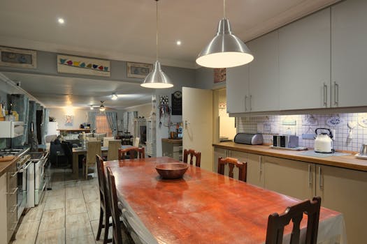 Spacious kitchen and dining room featuring contemporary design with warm lighting, located in a cozy home.