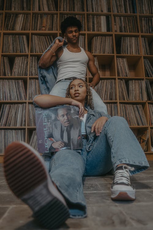 A couple sitting on the floor in front of a record store