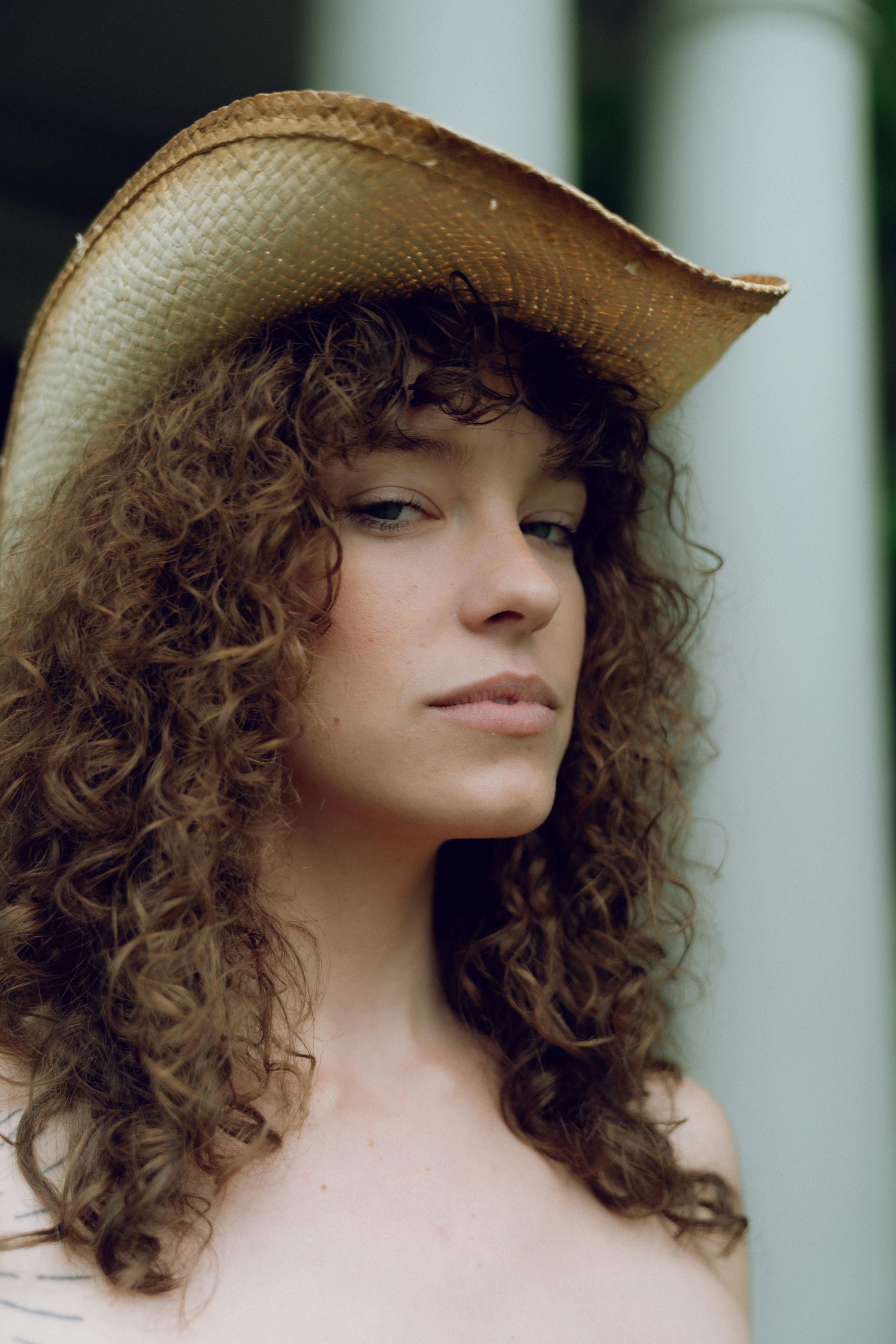 a woman with curly hair wearing a cowboy hat