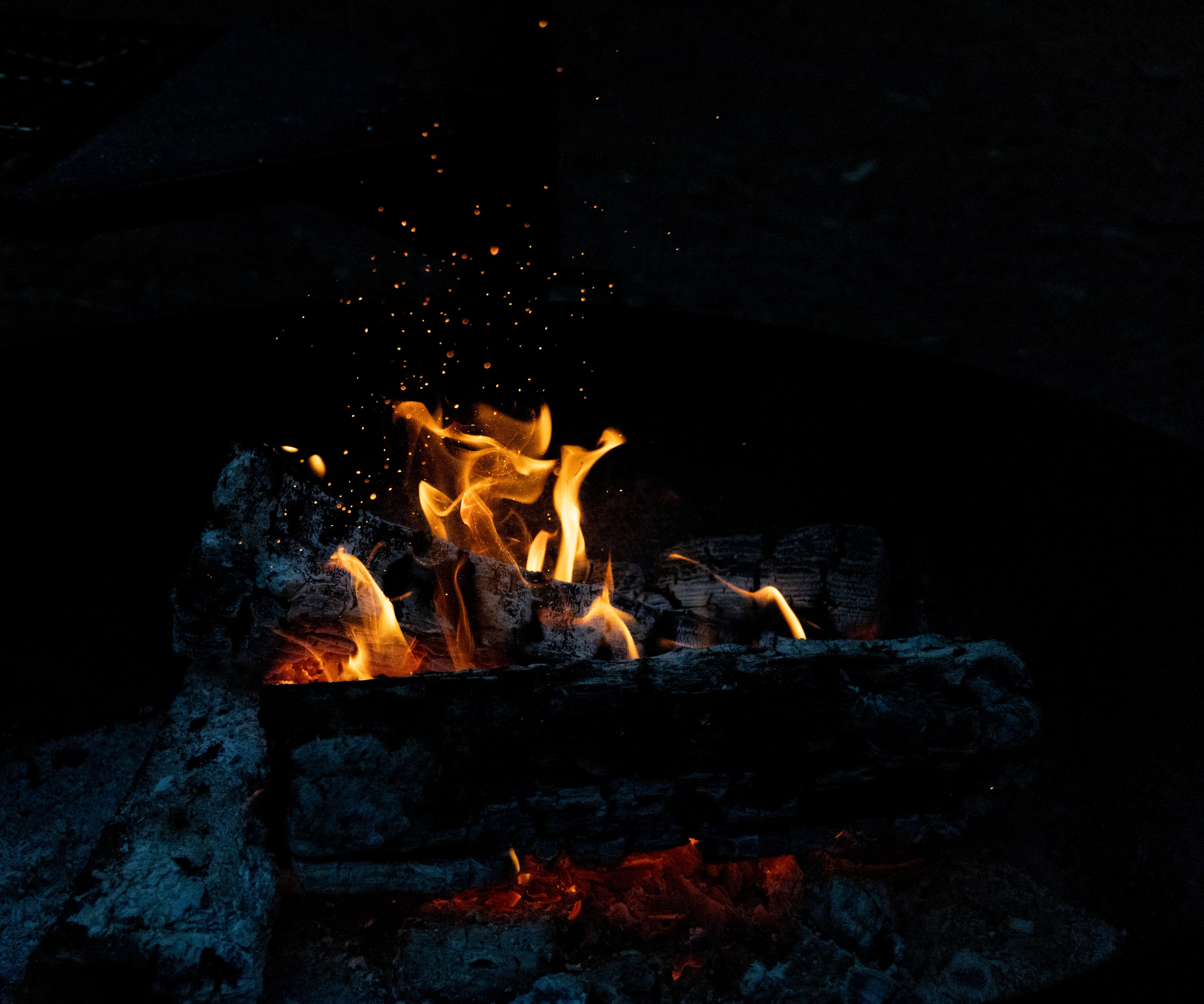 A campfire with flames and sparks in the dark · Free Stock Photo