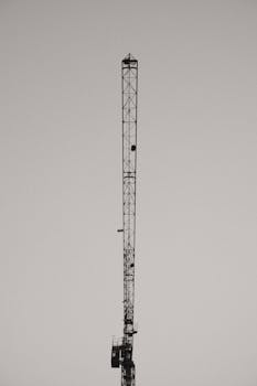 Monochrome image of a tall construction crane against a clear sky.