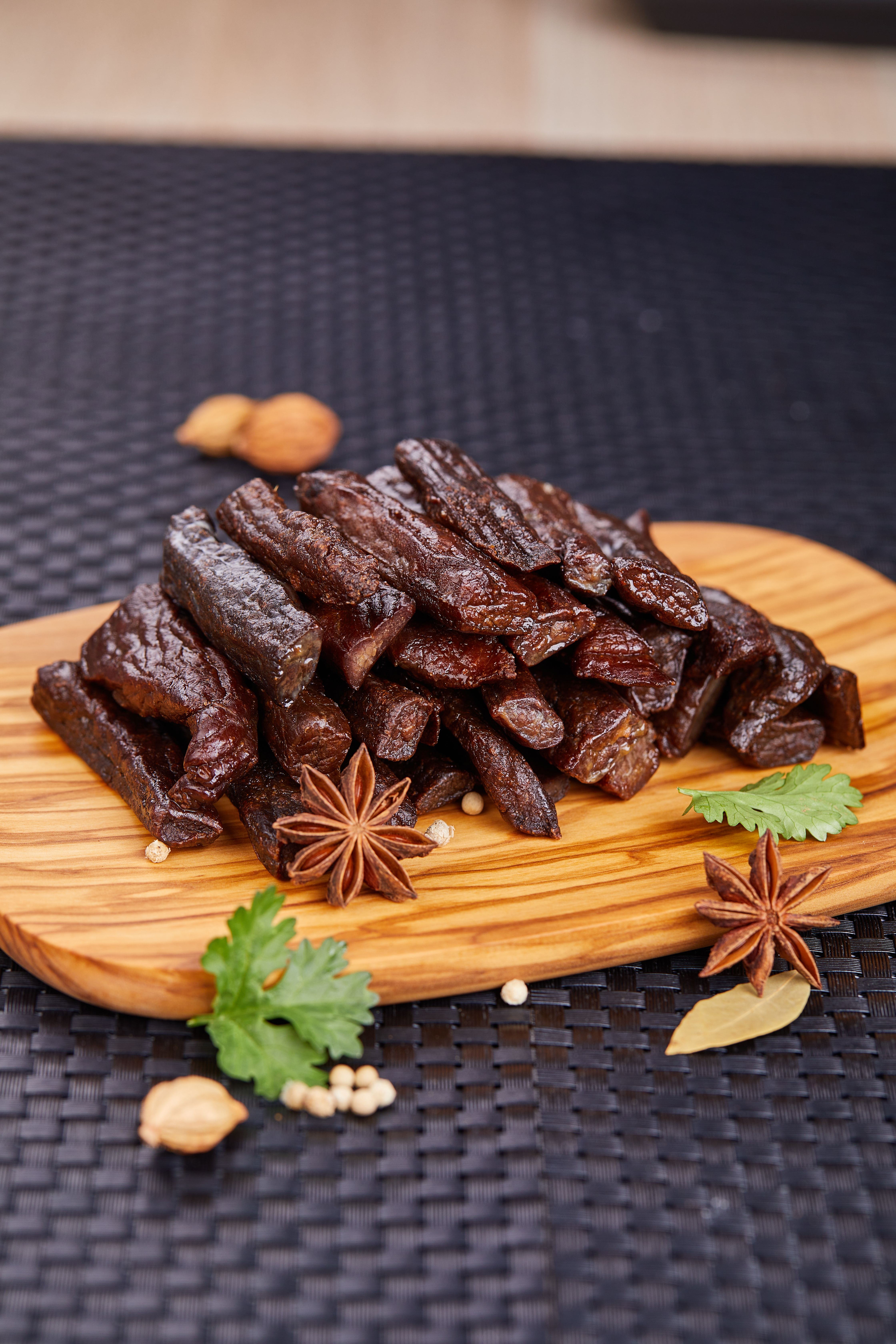 A stack of gourmet sausages on a wooden cutting board with aromatic spices.