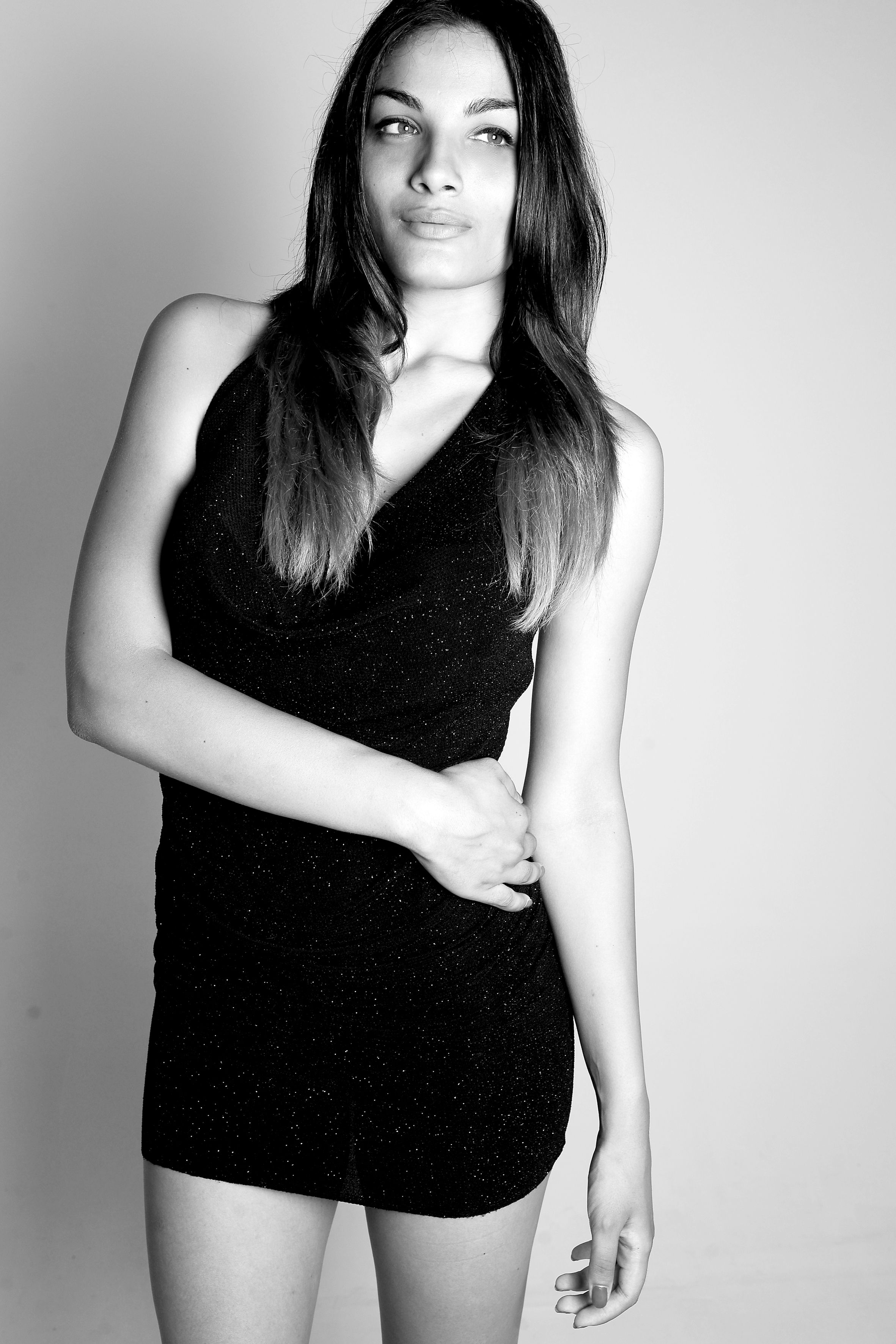Black and white portrait of a woman in a stylish dress in a studio setting.