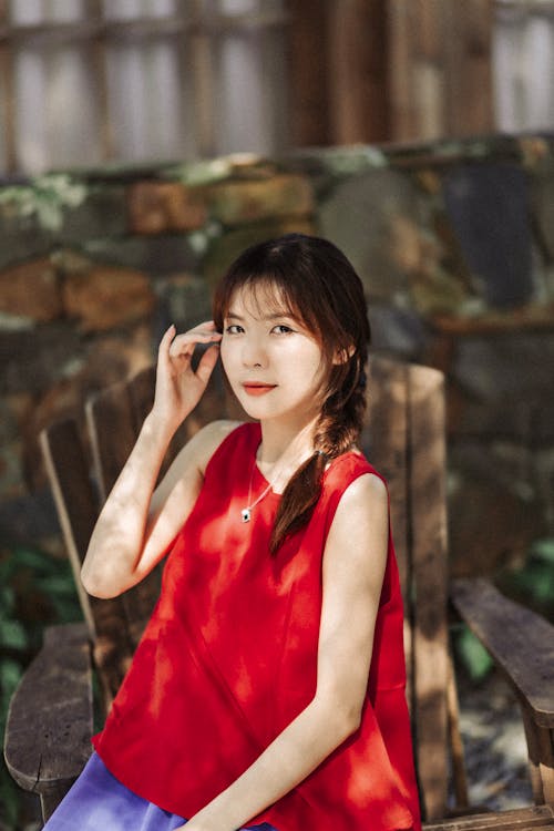 A woman sitting on a wooden chair talking on her cell phone