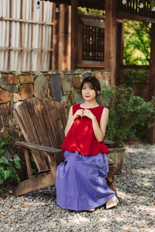 A woman in a red and blue skirt sitting on a wooden bench