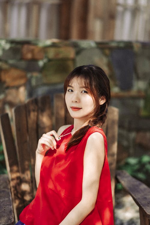 A woman in a red shirt sitting on a wooden bench