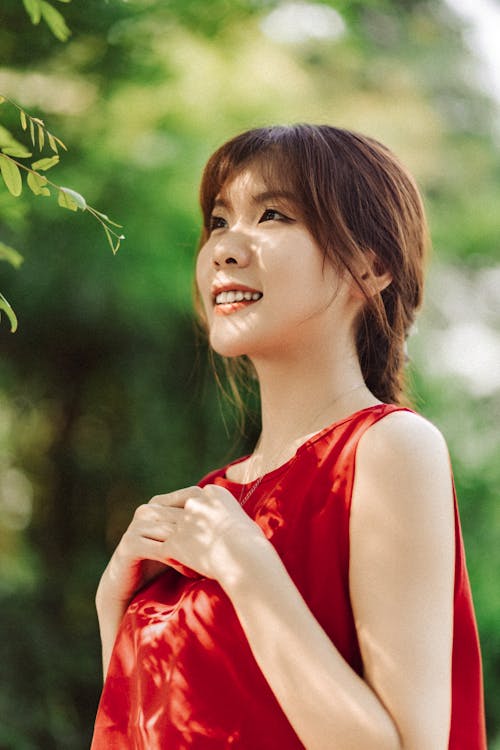 A woman in a red dress smiling and looking at the camera