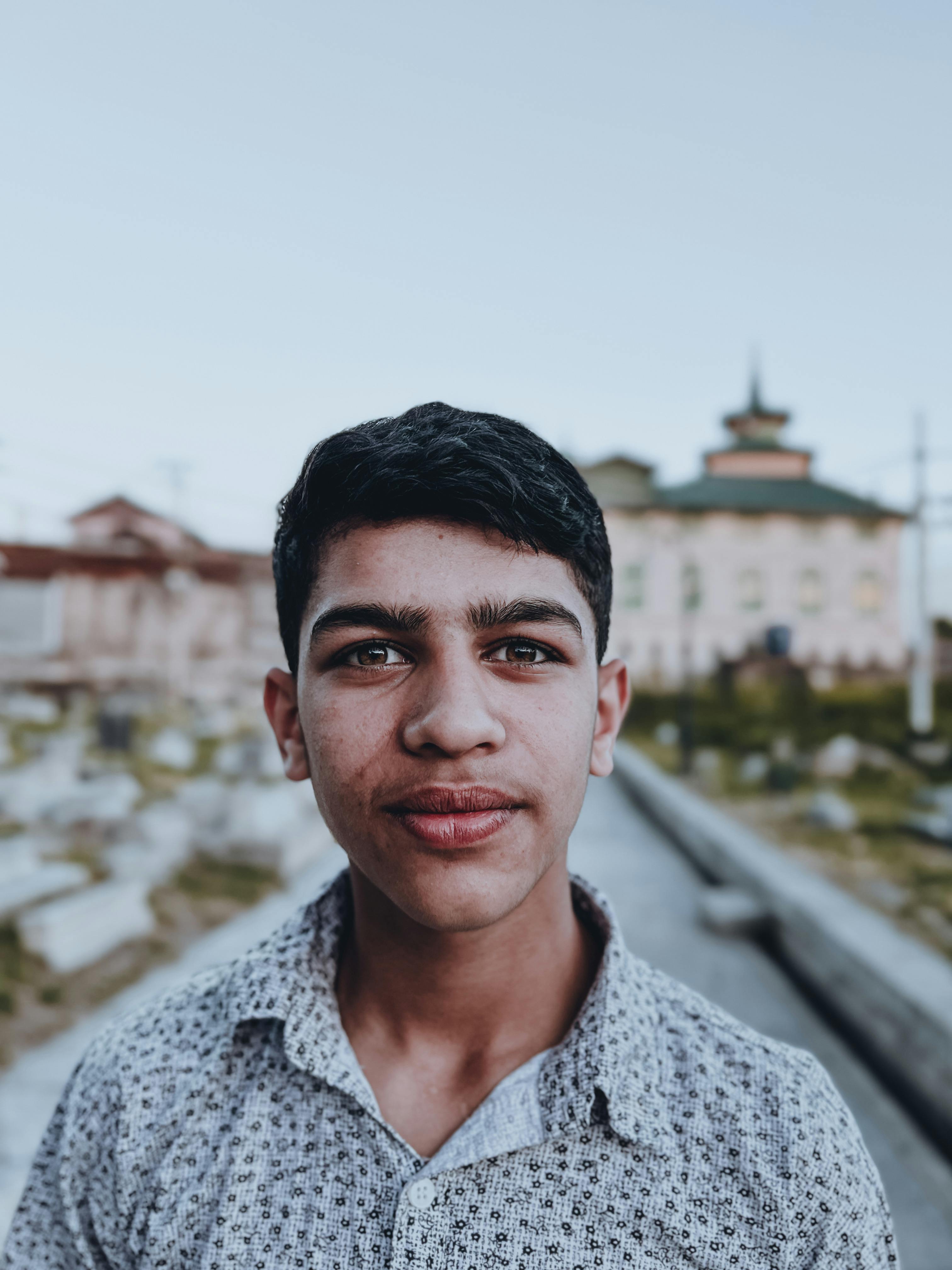 Close-up portrait of a young man standing outdoors in Srinagar, showcasing cultural attire.