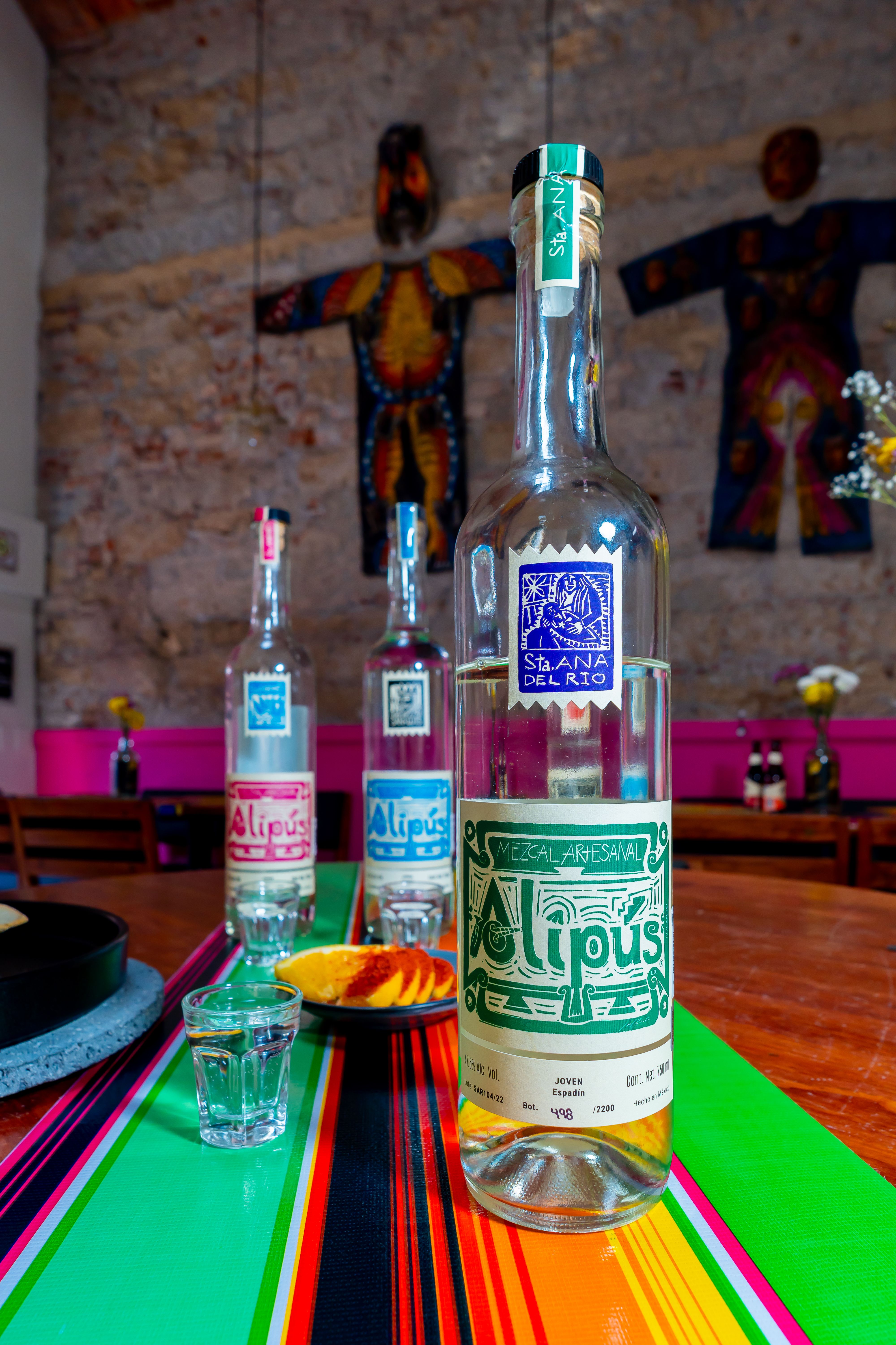 Vibrant Alipus mezcal bottles showcased in a lively Mexican setting.