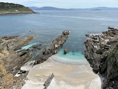 An unspoiled beach with rock formations and turquoise water on the coast of the Atlantic Ocean near Donòn, Cangas, Galicia, Spain, April 2023