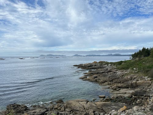 Rocky coast of the Atlantic Ocean with a blue sky and clouds near Balea, Cangas, Galicia, Spain, April 2023