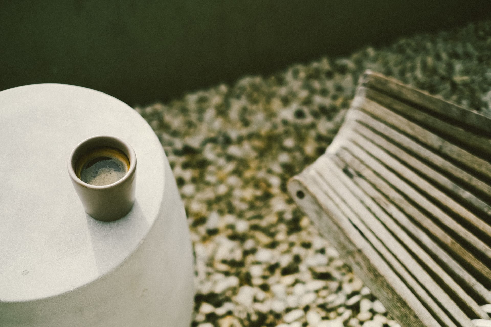 Artistic shot of a coffee cup on a minimalist concrete table with ambient lighting.