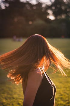 阳光明媚的公园里，一位黑发飘逸的成年女性充满活力，动态十足