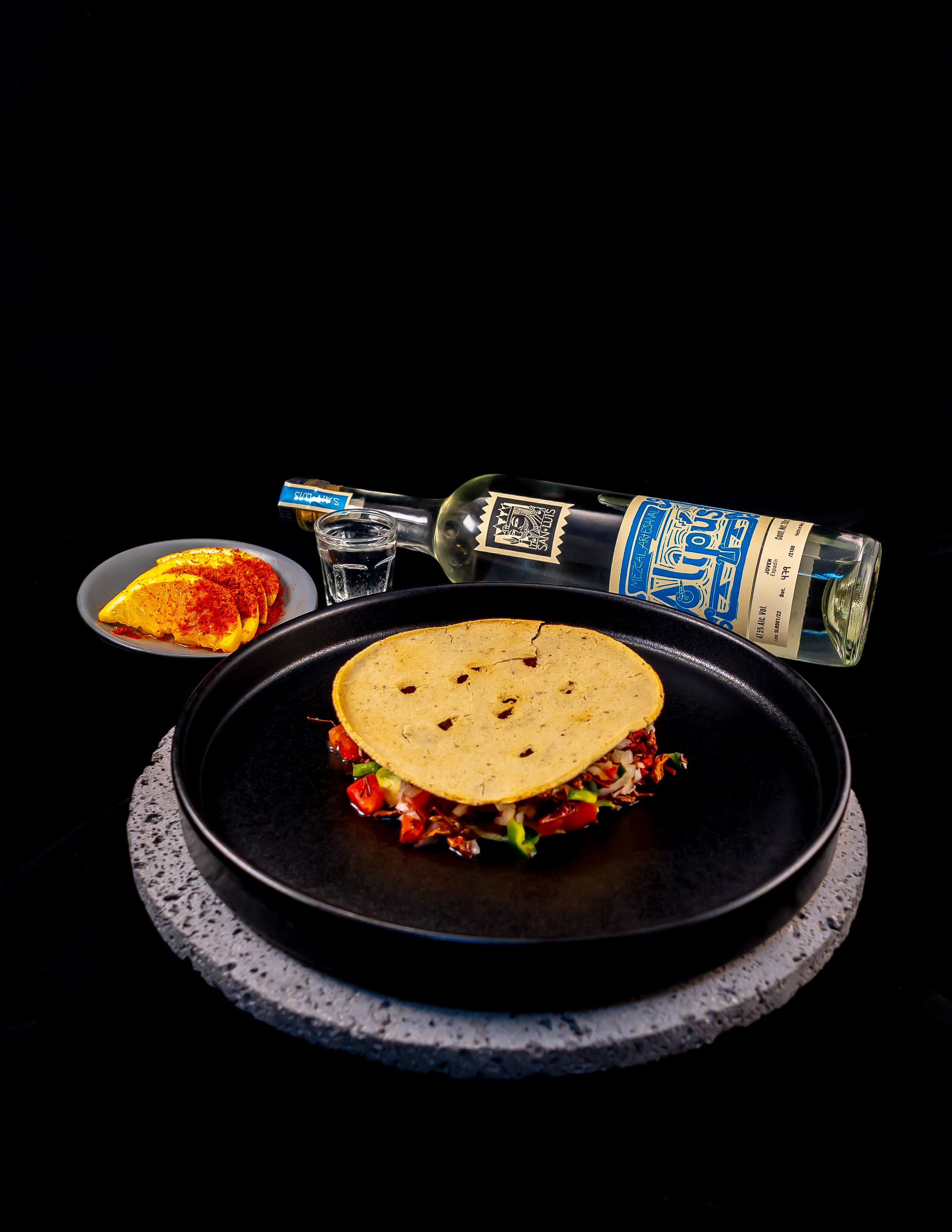 Authentic Mexican taco with Mezcal bottle, perfect for culinary presentations and food photography.
