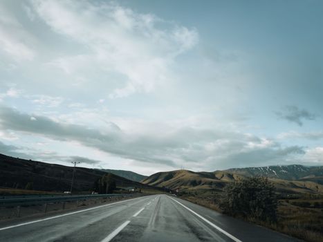 Beautiful mountainous landscape with a road leading into the distance under a cloudy sky.