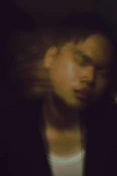 Artistic blurred portrait of a man with eyes closed, creating a double exposure effect.