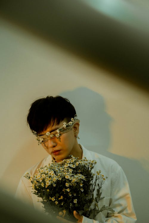 A man in glasses holding a bunch of flowers