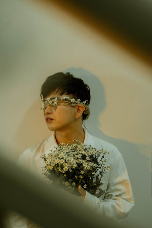 A man with glasses holding flowers