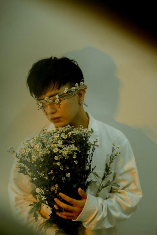 A young man with glasses holding flowers