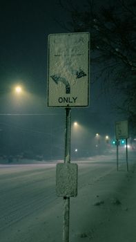 Street at night in Grand Rapids, MI under snow, glowing streetlights, and traffic signs.