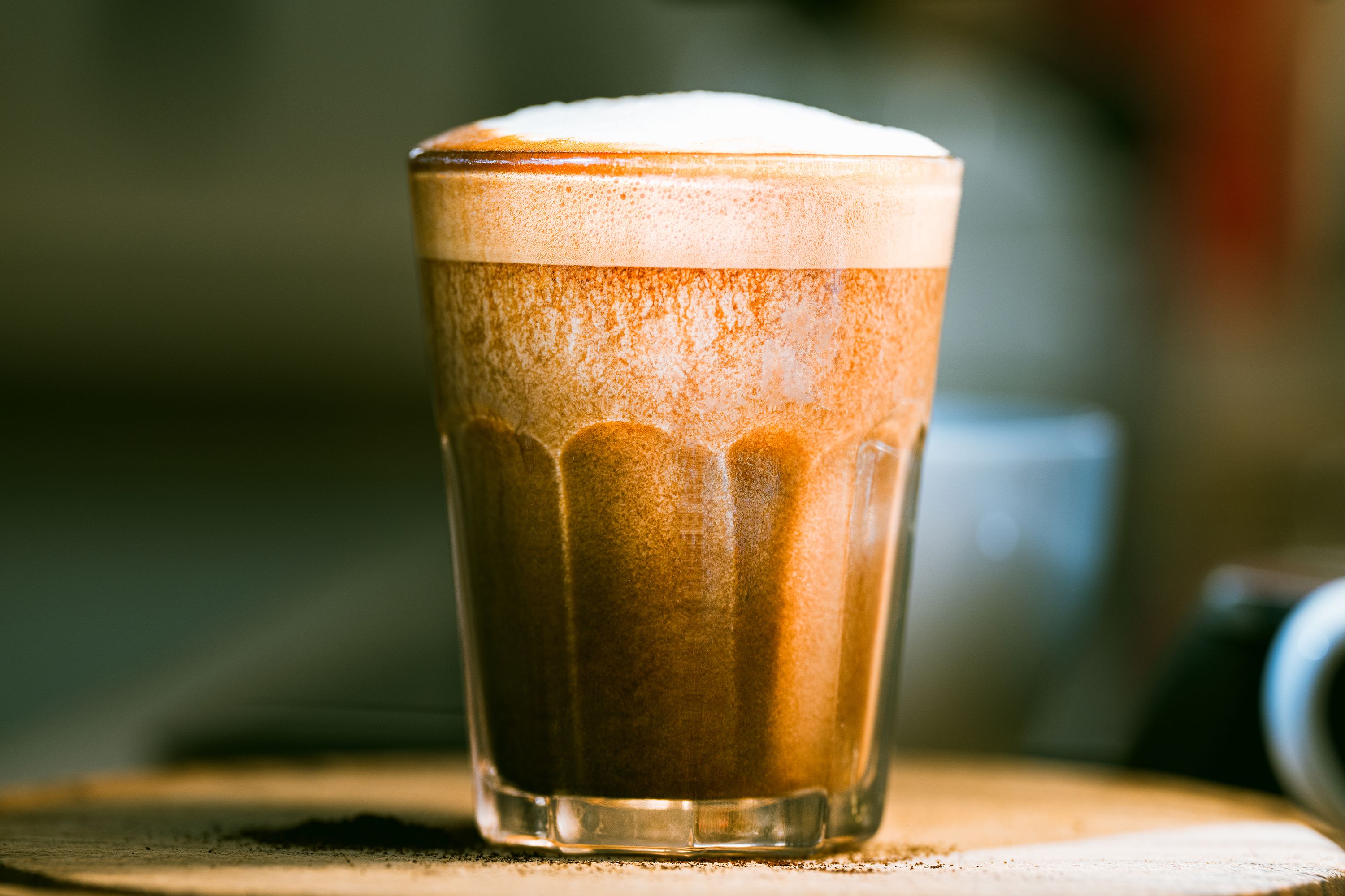 A rich, frothy cappuccino captured in a clear glass, emphasizing texture and warmth.