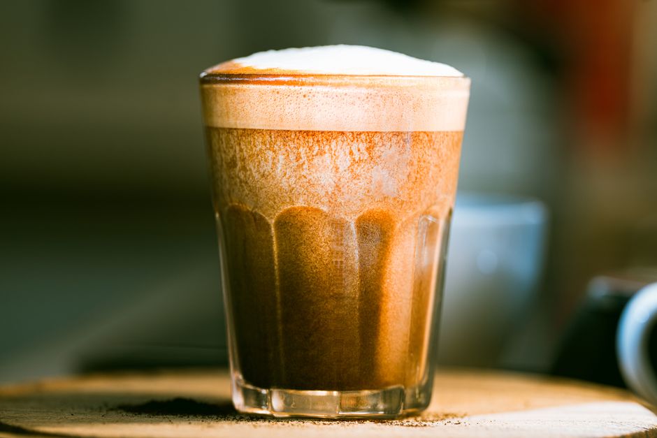 A rich, frothy cappuccino captured in a clear glass, emphasizing texture and warmth.