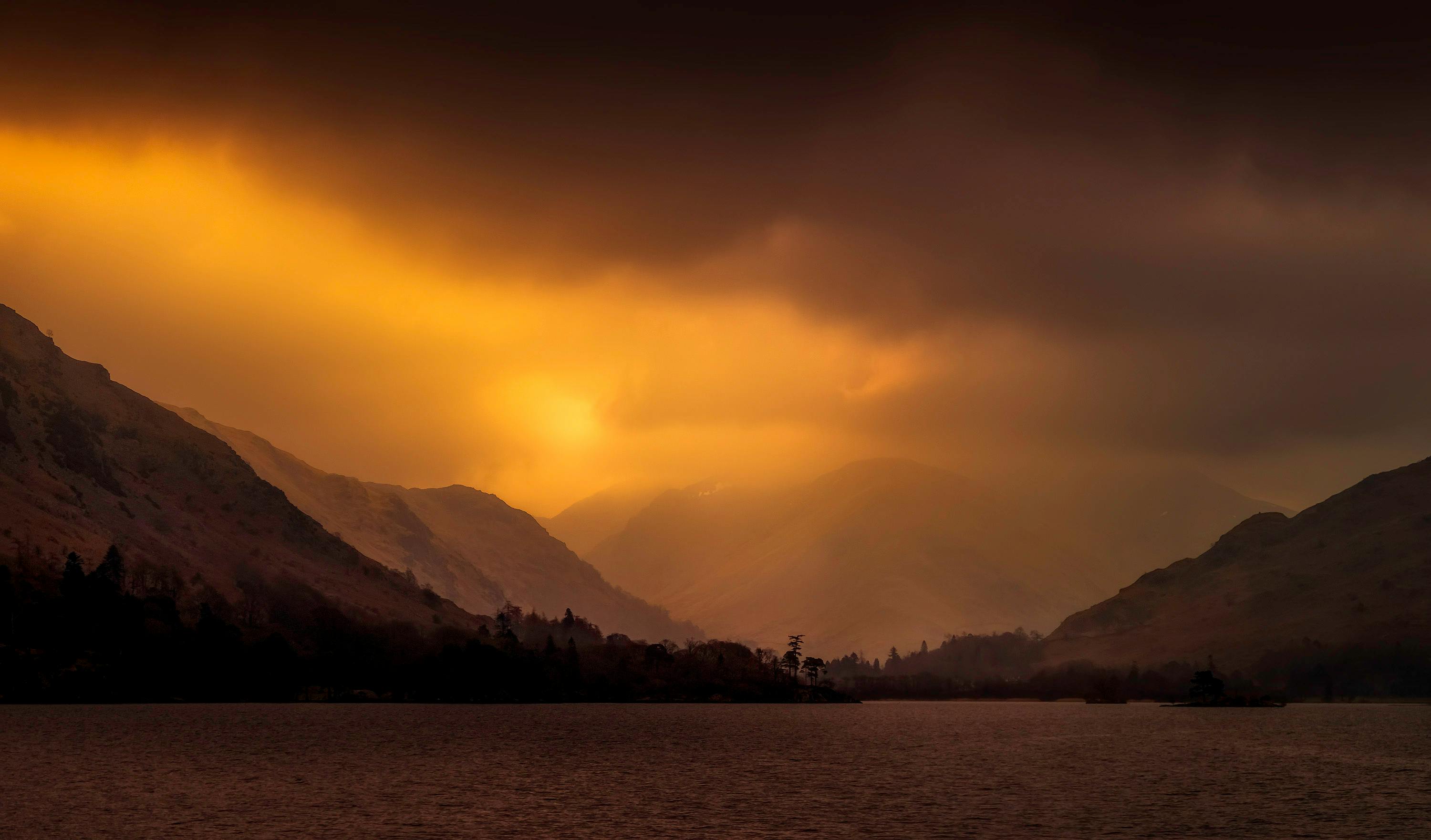山间宁静的湖泊上，日落景色壮观，山峰轮廓分明