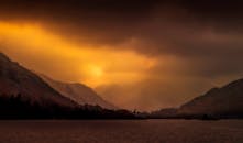 山间宁静的湖泊上，日落景色壮观，山峰轮廓分明