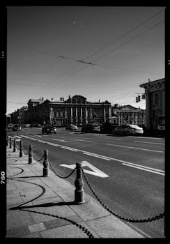 这是一张黑白照片，拍摄了繁忙的城市街道，以历史建筑和过往车辆为特色