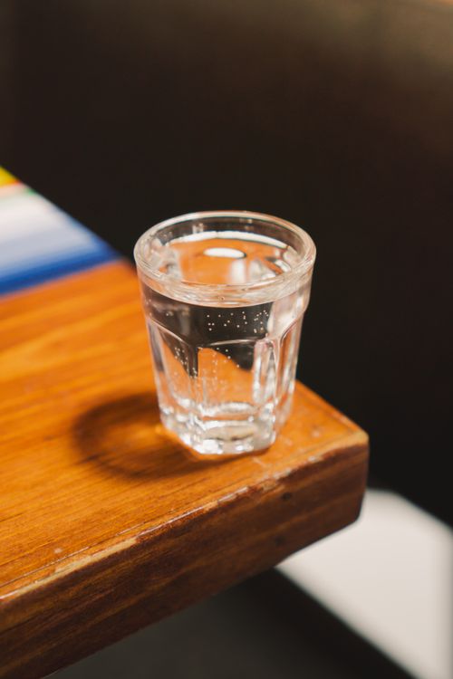 Free Close-up of a clear glass filled with water placed on a wooden table indoors. Stock Photo