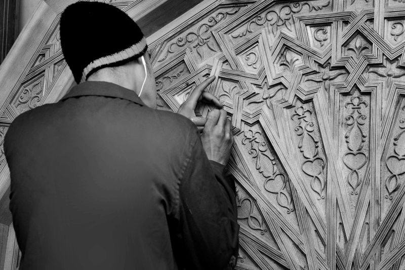 A craftsman in Fès, Morocco intricately carves wood with traditional techniques, showcasing detailed craftsmanship.