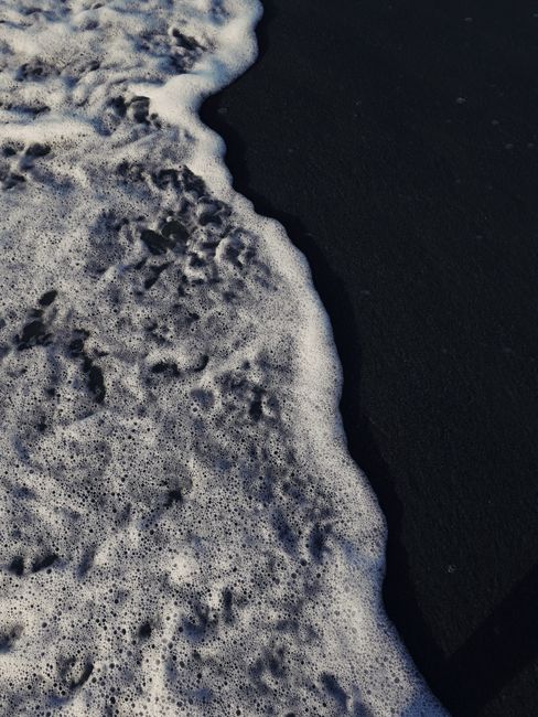 Fotomural Playa de arena negra con olas espumosas del océano en Agia Marina, Grecia.