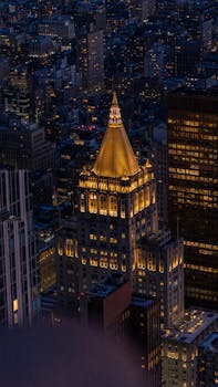 Dramatic night shot of the illuminated New York Life Building set against the Manhattan skyline.
