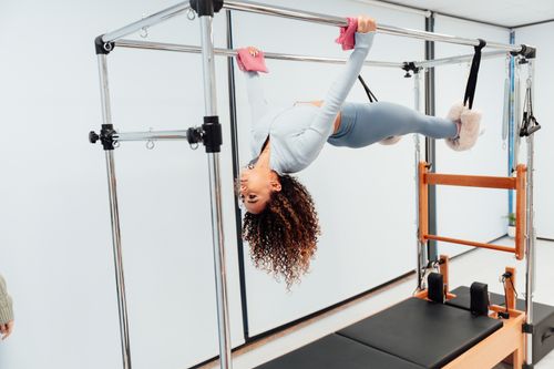 Free Fit woman doing pilates exercise on reformer equipment in a fitness studio. Stock Photo