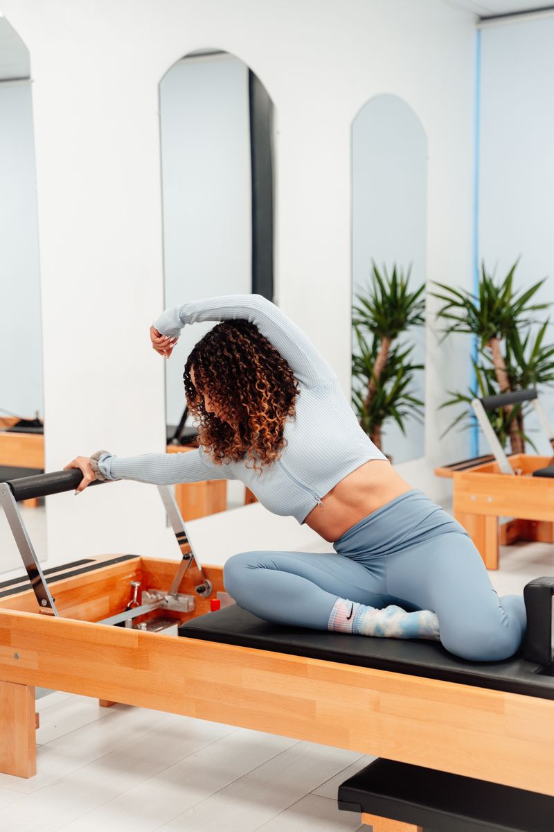 Woman practicing pilates on reformer machine, promoting healthy lifestyle indoors