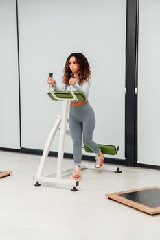 A young woman exercises on gym equipment indoors, promoting fitness and a healthy lifestyle.